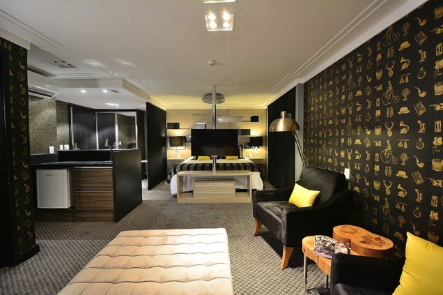 CASACOR Rio Grande do Sul 2015. Suíte New York - Cíntia Aguiar. O projeto dispensa as divisórias e prioriza a integração nestes 36 m², tendo como referência o estilo dos lofts. A circulação é livre, e a TV giratória traz mais mobilidade e conforto ao cotidiano. O uso de tons urbanos e sóbrios entra em sintonia com a proposta, presentes no papel de parede com desenhos vintage, na madeira ébano do mobiliário e mesmo nas louças da sala de banho. Repare que o tapete cinza se estende por todo o espaço, trazendo unidade visual. CASACOR Rio Grande do Sul 2015. Suíte New York - Cíntia Aguiar. O projeto dispensa as divisórias e prioriza a integração nestes 36 m², tendo como referência o estilo dos lofts. A circulação é livre, e a TV giratória traz mais mobilidade e conforto ao cotidiano. O uso de tons urbanos e sóbrios entra em sintonia com a proposta, presentes no papel de parede com desenhos vintage, na madeira ébano do mobiliário e mesmo nas louças da sala de banho. Repare que o tapete cinza se estende por todo o espaço, trazendo unidade visual.
