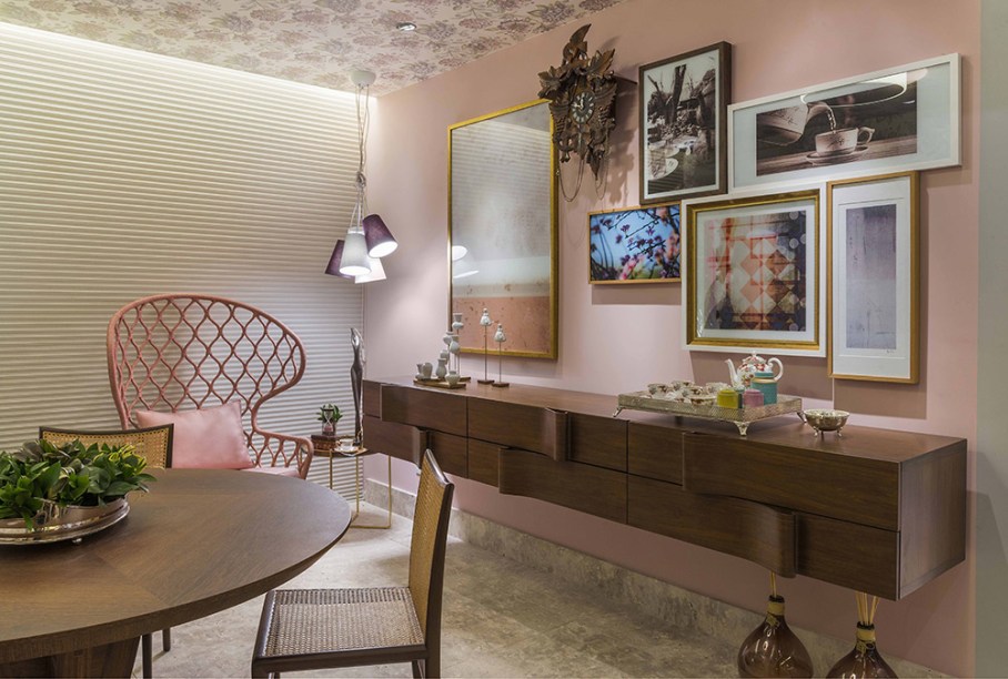 Sala de Chá - Caroline Napoleão e Fernando Rodrigues. A tradição do chá das cinco e a cor do ano, o rosa, foram algumas inspirações. Com apenas 17m², a sala recupera a história do chá a partir de peças originais inglesas, cuja delicadeza é referenciada no papel de parede floral aplicado no teto. Outro diálogo bem-vindo acontece entre a poltrona Painho, de Marcelo Rosenbaum, e o aparador Ondas, de Arthur Casas.