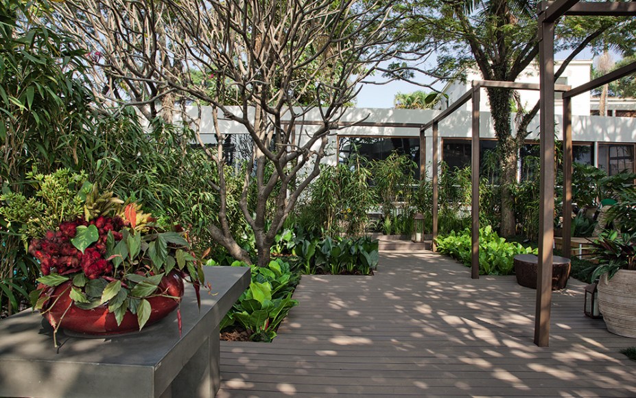 Jardim da Piscina - Pessuto Paisagismo. O paisagista Ricardo Pessuto assumiu o jasmim-manga, as palmeiras e a jabuticabeira do local como ponto de partida. Acrescentou vegetação com flores na parte mais ensolarada e optou, na área sombreada, por espécies como pacovás e asplênios. Para garantir a privacidade da piscina, ela foi abraçada por paredes de cobogós cimentícios. A iluminação também inova, localizada no topo das vigas de madeira.