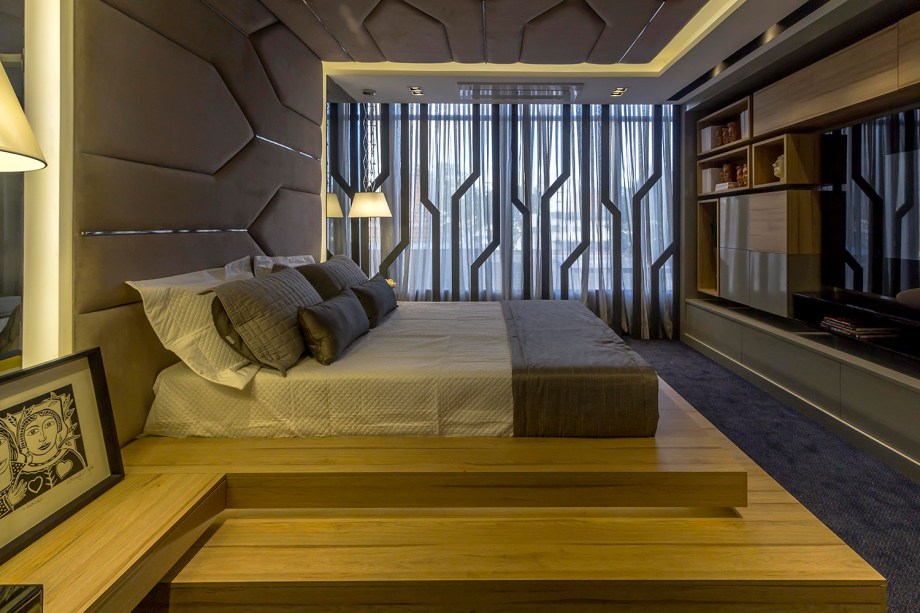 Quarto do Casal – Germana Terceiro Neto e Milena Regis. A cama instalada em um grande estrado de madeira é emoldurada pela cabeceira estofada com recortes geométricos, inspiradas nos cactos xique-xique do semiárido paraibano. As mesmas linhas se repetem na divisória.