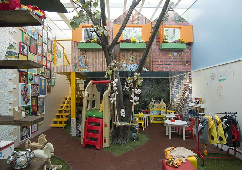 Brinquedoteca - Ana Ciarlini e Joanne Ximenes. Com cerca de 50m² de área construída, o espaço foi setorizado em lugar de leitura, cantinho dos brinquedos e uma casa mobiliada na árvore. Um detalhe na parede ganhou cor extra, com ladrilhos hidráulicos, enquanto o piso recebe um emborrachado produzido a partir de pneus e poliuretano reciclados. A árvore estilizada por Marcelo Angelim, delimitada pela grama sintética, traz o balanço em sisal do artesão Roberto Dias.