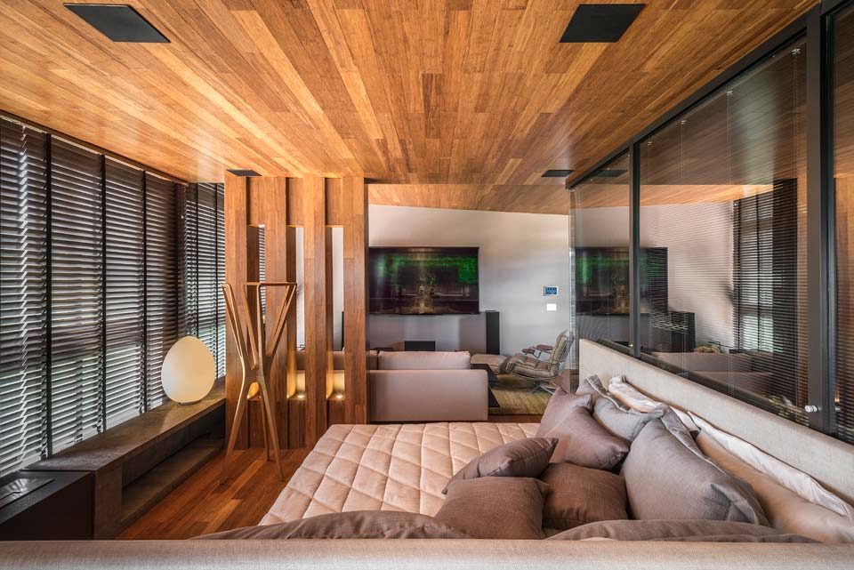 20-casa-cor-minas-ambientes-decorados-e-integrados-com-a-mata Studio Lumière. A arquiteta Flávia Zambelli reveste quase todo o ambiente com bambu, criando uma caixa aconchegante que agrada aos amantes da sétima arte, com excelente acústica. Persianas entre-vidros separam o banheiro do quarto, cuja cama de casal traz cabeceira em ráfia natural. Os tecidos também contém fibras naturais, que fazem contraponto ao aço corten da lareira.