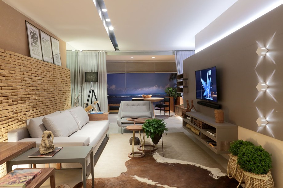 Apartamento Vista da Garça - Rosângela Carvalho. Esse ambiente de 128m² possui sala de estar, jantar, varanda gourmet e cozinha integrados e três suítes com banheiro reversível. Inspirado na beleza árida do sertão, possui decoração e mobiliário em tons e texturas que remetem à terra, à palha e à outros materiais típicos do nordeste brasileiro.