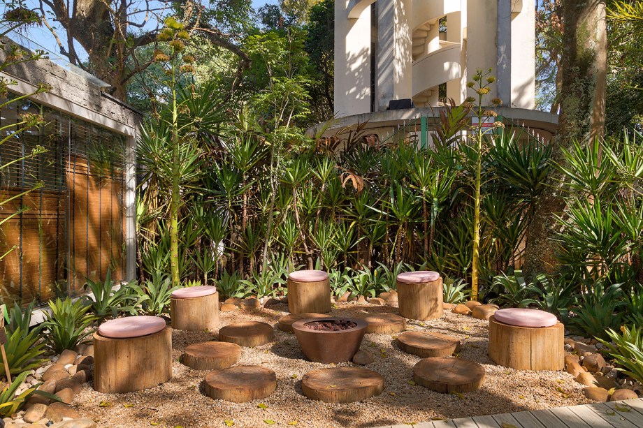 CASACOR São Paulo 2018. Jardim das Agaves - Gabriela Gaunszer Kozlowski e Rejane Heiden. O agave tradicional e em flor é protagonista, mas há outras plantas como a pinanga e a echevéria rosa contornando a área de convivência. O chão coberto de areia e pedras remete à cultura mexicana pré-colombiana. Tons de rosa, cinza e preto são trabalhados de forma natural e delicada no mobiliário.