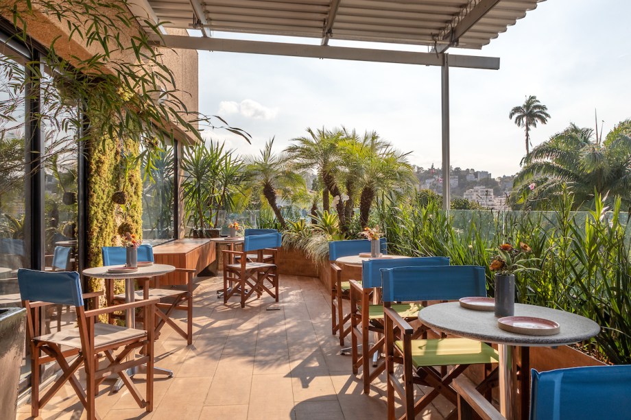 Terraço da Vista - Paula Neder e Viviane Menescal. A linda visão do terraço é redesenhada com a vegetação exuberante que contorna o espaço, ocupa algumas paredes e acolhe o visitante. As cadeiras que fazem uma releitura do modelo diretor trazem o conforto dos tecidos, em azul e verde - mesmos tons da paisagem.