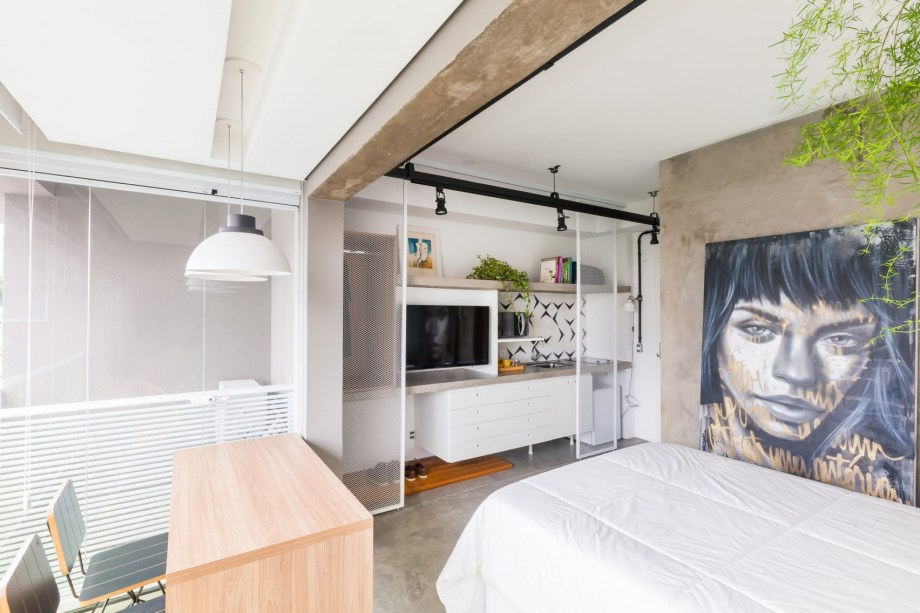 O escritório Casa 100 aproveitou ao máximo os 24 m² deste apartamento. A base do projeto são a cor branca e a textura de concreto, mostrando que bastam poucos elementos para trazer estilo. Uma ideia interessante foi utilizar portas de correr com telas quase transparentes. Elas delimitam a cozinha e o armário, sem fechar completamente o espaço para manter a leveza.