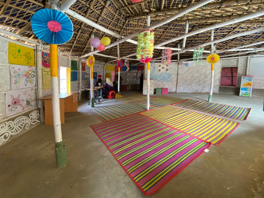 Vista de uma das salas centro comunitário com enfeites coloridos pendurados e desenhos nas paredes