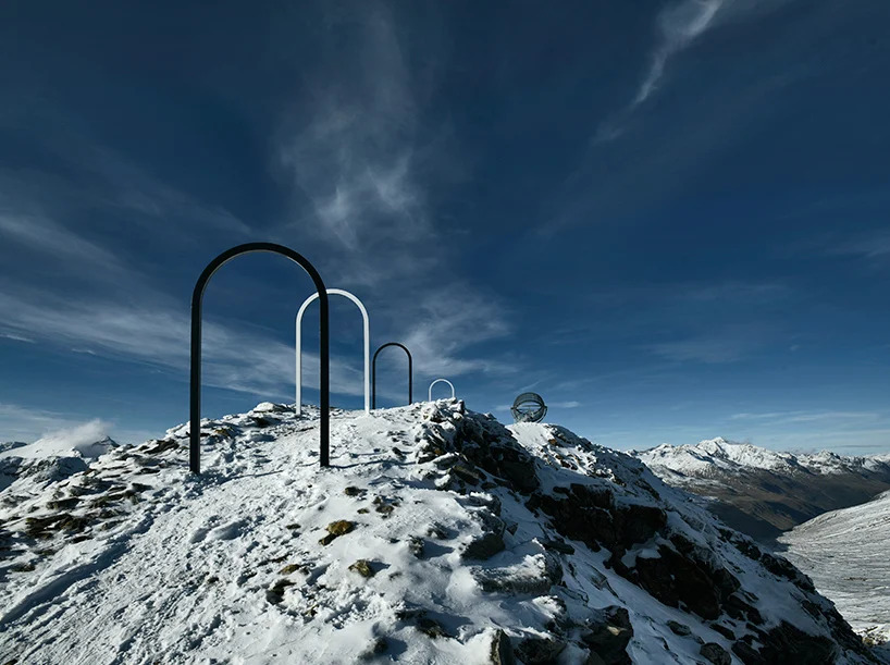 Portais em forma de arco brancos e pretos levando até estrutura artística no topo da montanha
