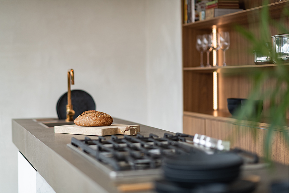 Detalhe na bancada com cooktop e uma tábua de madeira com um pão