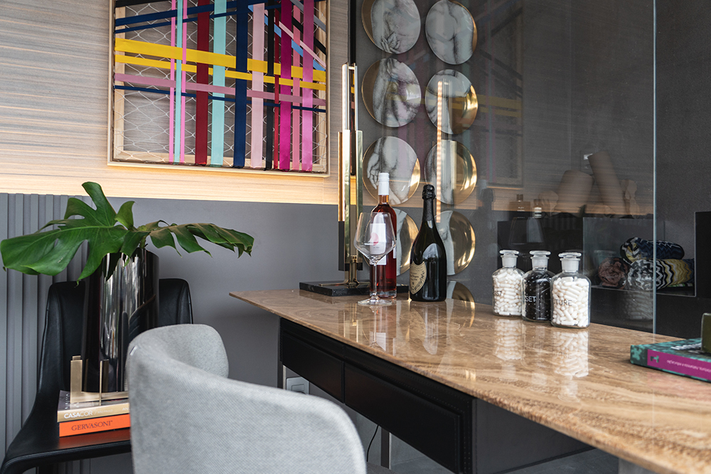 Mesa de trabalho com cadeira cinza e quadro colorido ao fundo