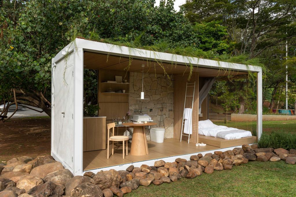 telhado-verde-casacor-estudio-elo-ticiane-lima-janelas-casacor-sao-paulo-2020-salvador-cordaro-6 Contêiner branco, com quarto, cozinha e banheiro com mobiliário e peças em madeira. Louças em branco e o telhado verde.