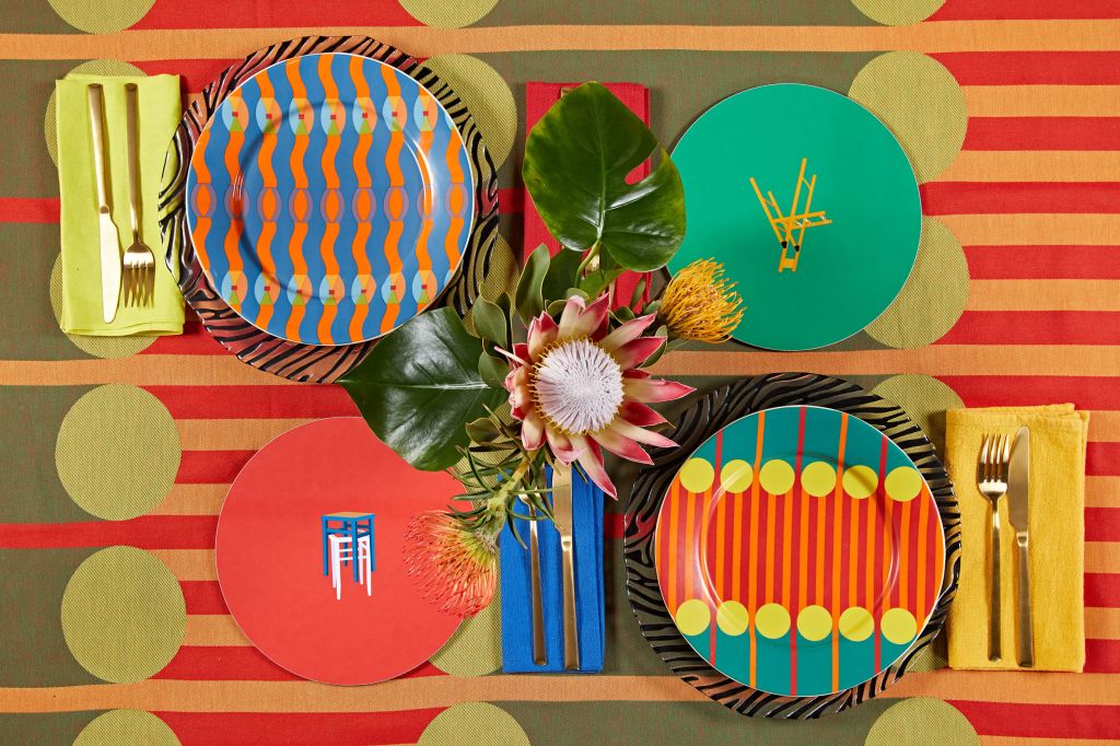 Imagem com quatro pratos sobre toalha da nova coleção e uma flor no centro