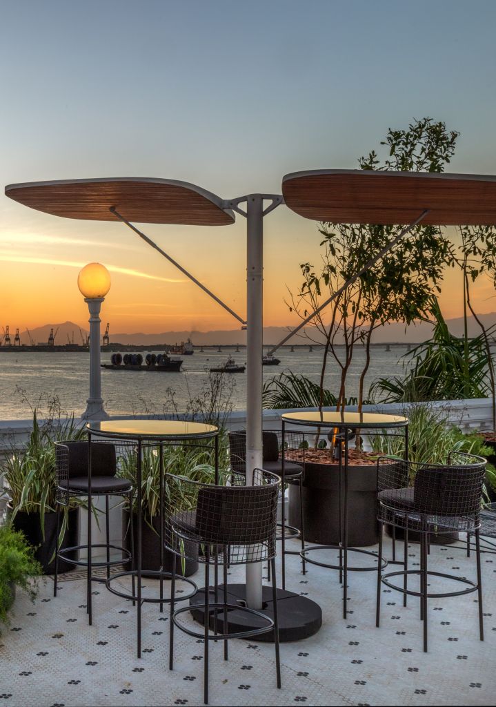 Gisele Taranto Arquitetura – CH’A Bar -002-2 Para-sol BIRD. Mesas e bancos pretos altos. Pôr do Sol ao fundo