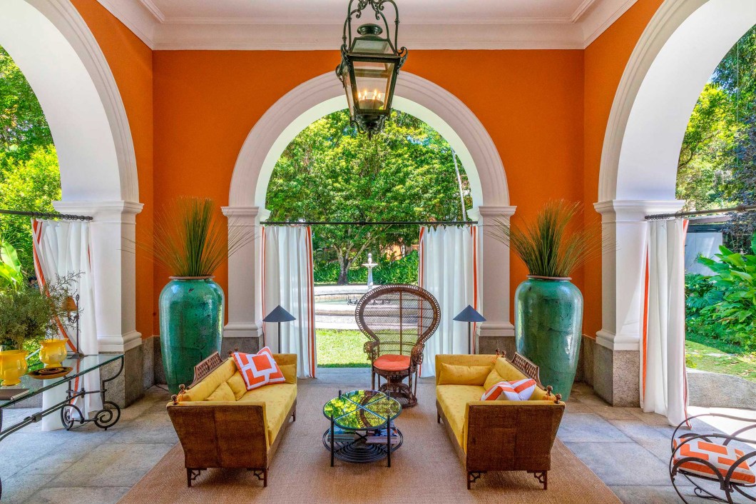 Cynthia Berlandez Pedrosa e Raphael Pedrosa Zay – Atrium. Pensado como uma varanda intimista em que se pudesse aproveitar a bela vista para os amplos jardins da residência, o antigo porte-cochère da casa ganhou ambientação casual chic com toques tropicais e o uso de materiais naturais como fibras e palha. Arcos brancos enquadram a natureza em volta. Cynthia Berlandez Pedrosa e Raphael Pedrosa Zay – Atrium. Pensado como uma varanda intimista em que se pudesse aproveitar a bela vista para os amplos jardins da residência, o antigo porte-cochère da casa ganhou ambientação casual chic com toques tropicais e o uso de materiais naturais como fibras e palha. Arcos brancos enquadram a natureza em volta.