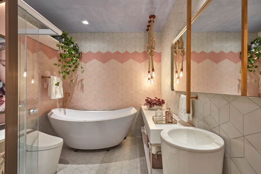 banheiro com paredes cor de rosa e uma planta suspensa na parte de cima da banheira branca