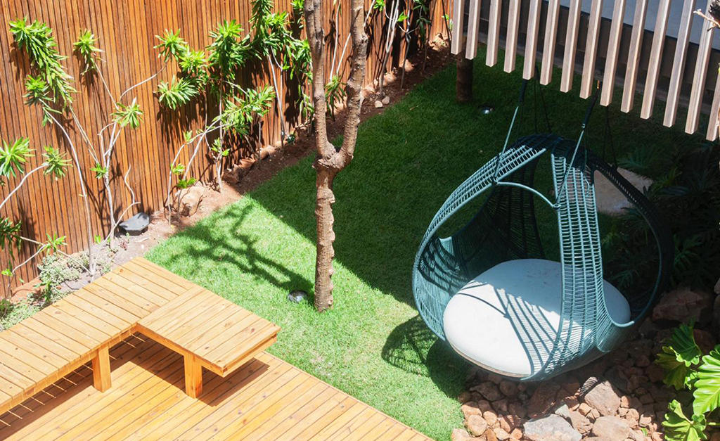area-externa-deck-pousada-maria-flor área externa da pousada maria flor com deck de madeira, grama verde e um puf azul turquesa para acomodar os visitantes
