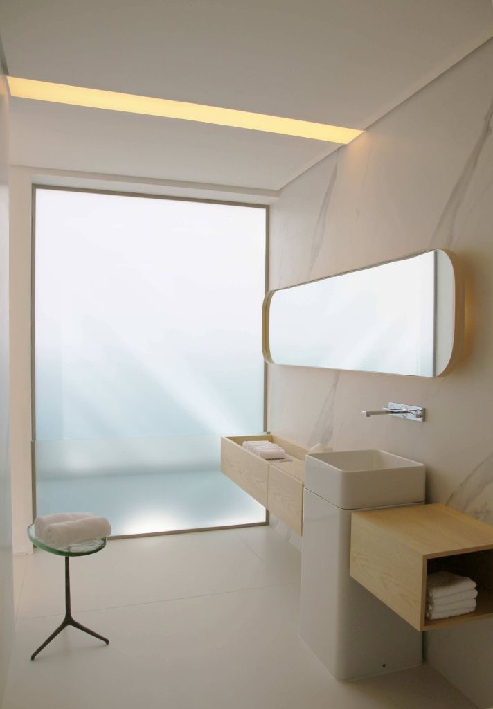 banheiro minimalista com ampla janela para o exterior, uma cuba com a torneira logo acima e um espelho amplo