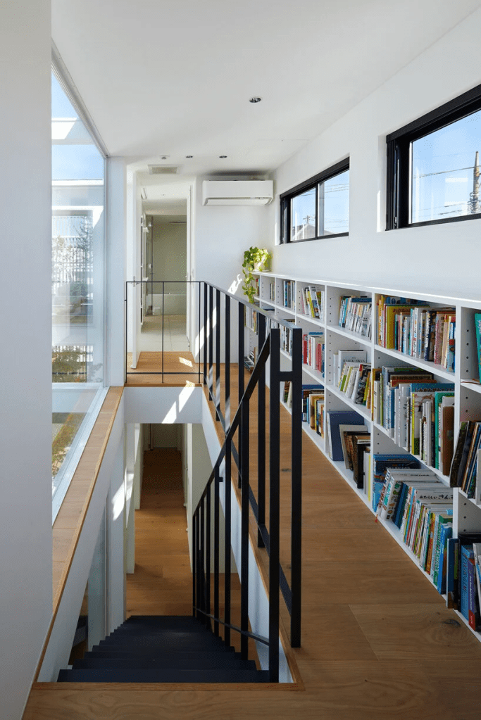 corredor com biblioteca projeto minimalista corredor que leva aos quartos conta com uma pequena estante metálica com livros, sem atrapalhar a passagem do projeto minimalista