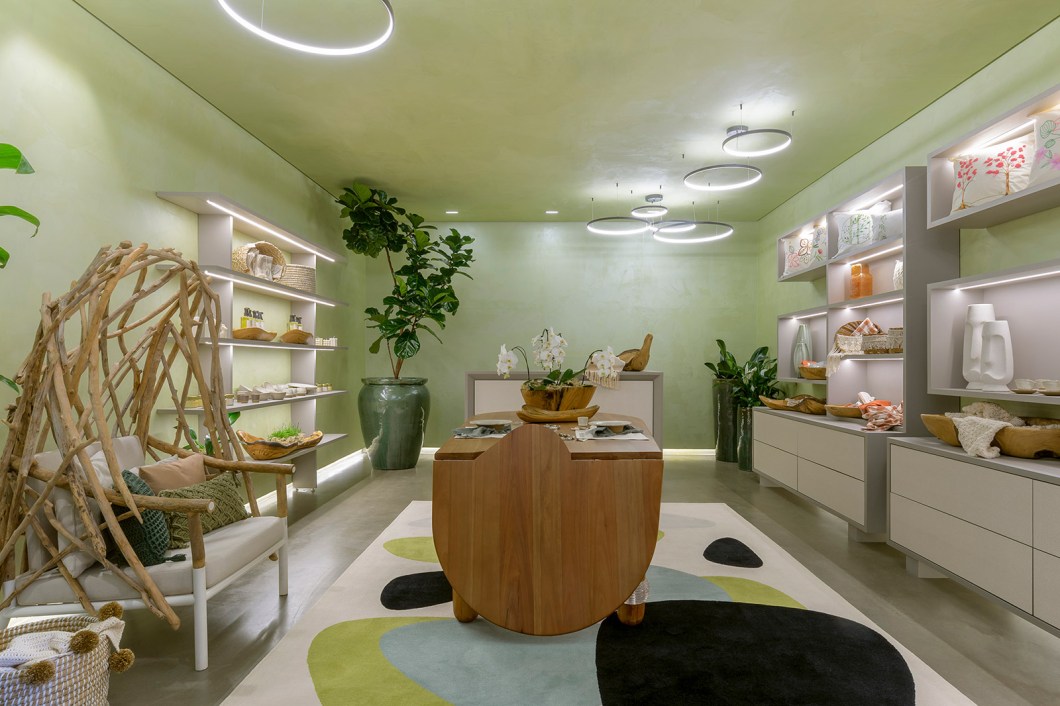 Carol Rosa - Loja Tempo. Este ambiente foi pensado ao se analisar sete variáveis: cores, formas, aromas, iluminação, biofilia, sons e personalização. O resultado é um espaço que gera conexão entre as pessoas e suas histórias. A arquiteta cria uma caixa verde de veludo, utilizando o efeito velvet na pintura da parede e brincando com os pendentes circulares na iluminação, para trazer uma sensação de tranquilidade ao usuário - assim ele conseguirá resgatar suas memórias e criará novas com os produtos comercializados. Carol Rosa - Loja Tempo. Este ambiente foi pensado ao se analisar sete variáveis: cores, formas, aromas, iluminação, biofilia, sons e personalização. O resultado é um espaço que gera conexão entre as pessoas e suas histórias. A arquiteta cria uma caixa verde de veludo, utilizando o efeito velvet na pintura da parede e brincando com os pendentes circulares na iluminação, para trazer uma sensação de tranquilidade ao usuário - assim ele conseguirá resgatar suas memórias e criará novas com os produtos comercializados.