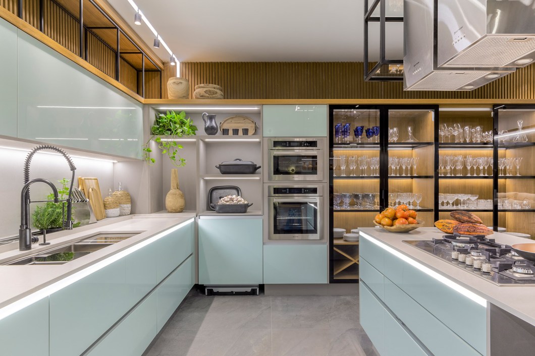 Rubiana Teixeira - Cozinha 21. Neste projeto, a profissional mescla a cozinha que segue as tendências da arquitetura atual com a cozinha raiz, buscando por meio dos detalhes remeter ao passado. Os revestimentos hexagonais em tons de azul referenciam os ladrilhos hidráulicos bastante usados antigamente. O tom menta da marcenaria junto â madeira forma uma composição equilibrada que aquece e traz aconchego ao espaço. O mobiliário de ferro curvo, as banquetas de couro e as peças de artesanato da decoração compõem toda a essência da Cozinha 21. Rubiana Teixeira - Cozinha 21. Neste projeto, a profissional mescla a cozinha que segue as tendências da arquitetura atual com a cozinha raiz, buscando por meio dos detalhes remeter ao passado. Os revestimentos hexagonais em tons de azul referenciam os ladrilhos hidráulicos bastante usados antigamente. O tom menta da marcenaria junto â madeira forma uma composição equilibrada que aquece e traz aconchego ao espaço. O mobiliário de ferro curvo, as banquetas de couro e as peças de artesanato da decoração compõem toda a essência da Cozinha 21.