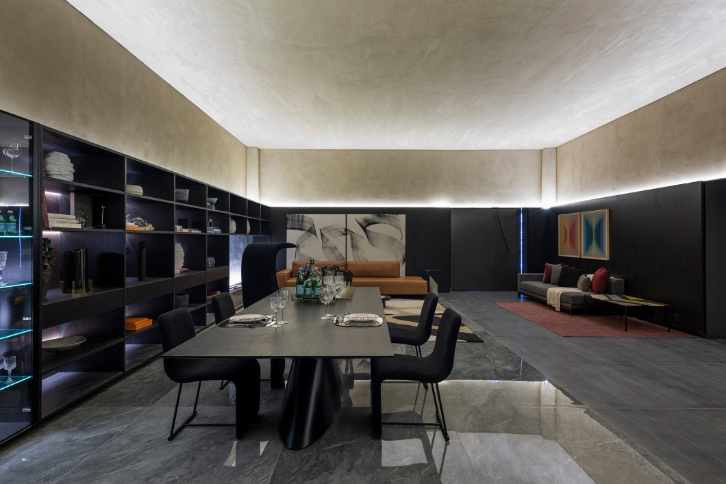 Arthur Guimarães - Lounge Comandante Rolim Amaro. No ambiente que marca a entrada da mostra, o arquiteto propõe um lounge de primeira classe para os visitantes “se sentirem em casa”. “Depois de um período de isolamento, quis trazer a aviação como símbolo da nossa mobilidade”, conta. Com sala de estar e jantar, adega climatizada e lavatórios, o espaço de 110 m² apresenta mobiliário contemporâneo, obras de arte, fotografias e tapete produzido a partir de resíduos da indústria têxtil. Destaque para os lavatórios, desenhados por Arthur Guimarães para o ambiente, são de mármore italiano, em coloração vinho vívida e intensa. Arthur Guimarães - Lounge Comandante Rolim Amaro. No ambiente que marca a entrada da mostra, o arquiteto propõe um lounge de primeira classe para os visitantes “se sentirem em casa”. “Depois de um período de isolamento, quis trazer a aviação como símbolo da nossa mobilidade”, conta. Com sala de estar e jantar, adega climatizada e lavatórios, o espaço de 110 m² apresenta mobiliário contemporâneo, obras de arte, fotografias e tapete produzido a partir de resíduos da indústria têxtil. Destaque para os lavatórios, desenhados por Arthur Guimarães para o ambiente, são de mármore italiano, em coloração vinho vívida e intensa.