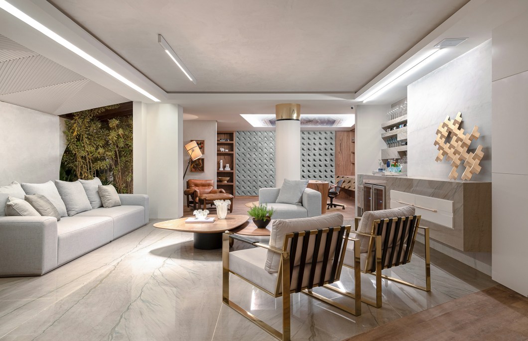 Ana Paula Moreira - Living do Bem Viver. O amplo ambiente tem adega esculpida em mármore, sofá de medidas generosas e mesa multifuncional que pode ser usada também para o home office. A integração é possível graças à marcenaria planejada. O estilo da designer de interiores se fez presente com a mescla entre o contemporâneo e o clássico. A poltrona Mole, de Sérgio Rodrigues, convida ao relaxamento. Cobogós e jardim trazem frescor e deixam a luz entrar. A atmosfera fica completa com o projeto de iluminação que ressalta os detalhes do projeto. Ana Paula Moreira - Living do Bem Viver. O amplo ambiente tem adega esculpida em mármore, sofá de medidas generosas e mesa multifuncional que pode ser usada também para o home office. A integração é possível graças à marcenaria planejada. O estilo da designer de interiores se fez presente com a mescla entre o contemporâneo e o clássico. A poltrona Mole, de Sérgio Rodrigues, convida ao relaxamento. Cobogós e jardim trazem frescor e deixam a luz entrar. A atmosfera fica completa com o projeto de iluminação que ressalta os detalhes do projeto.