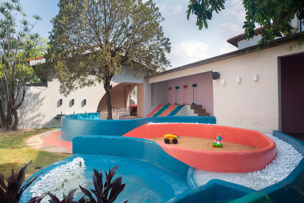Ana Luiza Giacomini - Jardim Colorido. Latas de tinta derramam cores em um ambiente totalmente neutro, trazendo vida e alegria. Do escorrega, as cores se espalham pelo ambiente e formam setores com as atividades infantis, fazendo alusão ao termo "caí na tinta". Os painéis em macramê e o muro pintado à mão com desenho para as crianças colorirem merecem atenção especial, ambos cuidadosamente feitos por artesão e artista plástica. No centro do ambiente, uma árvore que faz parte da história do imóvel, foi a chave de todo o projeto, criado e executado ao seu entorno. Ana Luiza Giacomini - Jardim Colorido. Latas de tinta derramam cores em um ambiente totalmente neutro, trazendo vida e alegria. Do escorrega, as cores se espalham pelo ambiente e formam setores com as atividades infantis, fazendo alusão ao termo "caí na tinta". Os painéis em macramê e o muro pintado à mão com desenho para as crianças colorirem merecem atenção especial, ambos cuidadosamente feitos por artesão e artista plástica. No centro do ambiente, uma árvore que faz parte da história do imóvel, foi a chave de todo o projeto, criado e executado ao seu entorno.