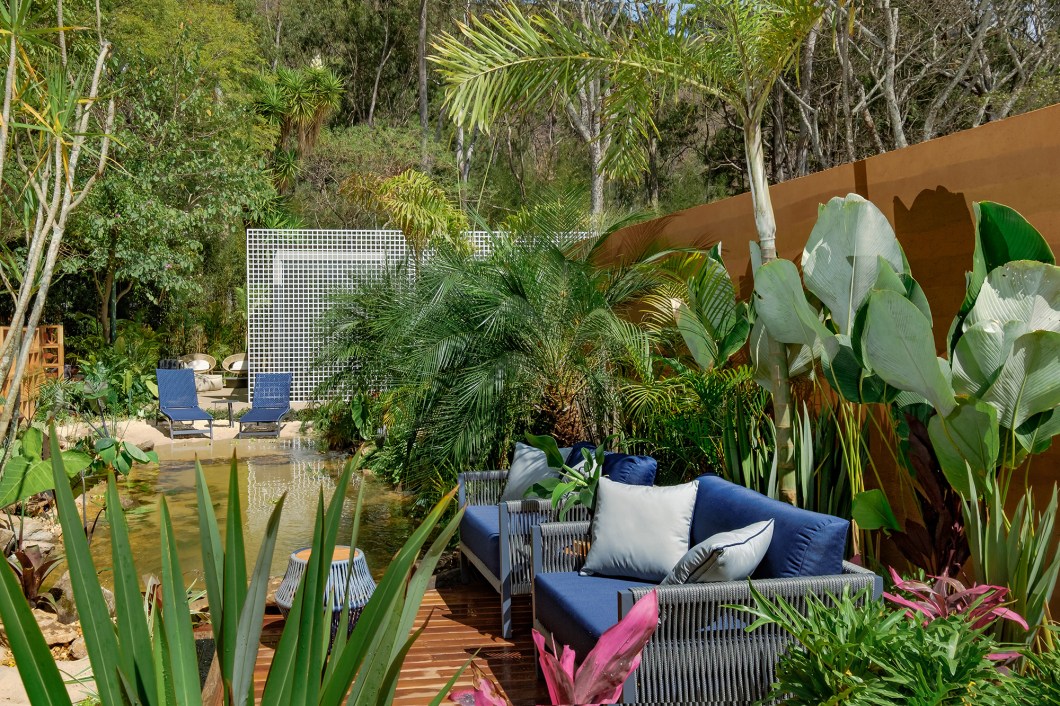 Rafael Mineiro e Natália Azevedo - Horto Laguna. Projeto da CASACOR Minas Gerais 2021. O espaço externo é um pequeno oásis, que traz diversidade de plantas tropicais em torno de um lago natural e propõe um novo conceito de piscina. Com leds submersos nas águas, em meio a palmeiras, filodendros, ciclantos, marantas e plantas aquáticas ganham uma iluminação difusa e a companhia de peixes ornamentais. Decks com poltronas e espreguiçadeiras integram o cenário de lazer e contemplação com um novo jeito de morar.