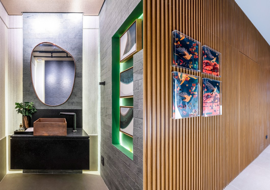 Elaine Vilela de Sousa - Banheiro Unissex Brasilidade. Em sua primeira vez na CASACOR, a designer de interiores traz a brasilidade como elemento criador de aconchego, representada especialmente na paleta de cores. Tons de verde da floresta amazônica estão no revestimento cerâmico que envolve as paredes do ambiente de 20 m², além da tela solar com iluminação, que se estende pelo hall de entrada. O ripado de madeira e a palha aplicada no forro completam o clima intimista, que prima pelos materiais naturais. Elaine Vilela de Sousa - Banheiro Unissex Brasilidade. Em sua primeira vez na CASACOR, a designer de interiores traz a brasilidade como elemento criador de aconchego, representada especialmente na paleta de cores. Tons de verde da floresta amazônica estão no revestimento cerâmico que envolve as paredes do ambiente de 20 m², além da tela solar com iluminação, que se estende pelo hall de entrada. O ripado de madeira e a palha aplicada no forro completam o clima intimista, que prima pelos materiais naturais.