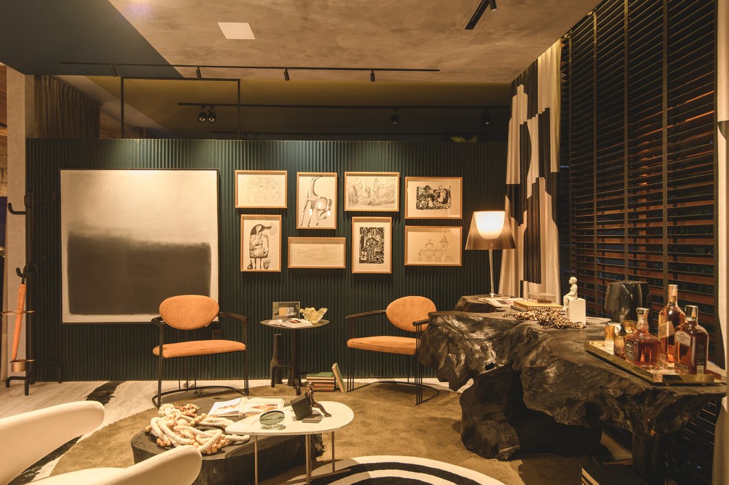 Diego Carneiro Arquitetos - Sala de Jantar do Amante das Artes. Na lista de inspirações está a arquitetura brutalista, com características como o minimalismo e a mostra dos materiais reais nas edificações (uma herança do projeto original da casa), além de referências com as obras de Athos Bulcão. O espaço conta com dois setores: a sala de jantar, com mesa autoral; e o lounge bar, composto por poltronas confortáveis e arrojadas e um aparador em tronco de raízes de madeira ebanizado. Destaque também para o piso em mármore e o jardim vertical com espécies nativas e tropicais. Na cartela de cores, a combinação contrastante de preto e branco. A iluminação é composta por um backlight acima das pérgolas de concreto, permitindo a entrada da luz natural. Diego Carneiro Arquitetos - Sala de Jantar do Amante das Artes. Na lista de inspirações está a arquitetura brutalista, com características como o minimalismo e a mostra dos materiais reais nas edificações (uma herança do projeto original da casa), além de referências com as obras de Athos Bulcão. O espaço conta com dois setores: a sala de jantar, com mesa autoral; e o lounge bar, composto por poltronas confortáveis e arrojadas e um aparador em tronco de raízes de madeira ebanizado. Destaque também para o piso em mármore e o jardim vertical com espécies nativas e tropicais. Na cartela de cores, a combinação contrastante de preto e branco. A iluminação é composta por um backlight acima das pérgolas de concreto, permitindo a entrada da luz natural.