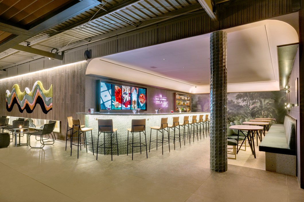 Studio Freijó - Altas Gastrobar. O espaço de 68 m² se inspira no estilo Neo Déco dos primeiros bares de coquetéis equilibrado com o tropicalismo do bar original do Altas. O projeto da arquiteta Natalie Tramontini e da designer de interiores Thalita Gonçalves, dupla à frente do Studio Freijó, tem rebuscamento nos materiais, como o veludo do banco, quartzito e porcelanato com acabamento metálico das paredes. Destaque para os acabamentos com diferentes texturas que compõem o ambiente. No local, obra de Carolina Kroff e um mural de Desireé Feldmann. Studio Freijó - Altas Gastrobar. O espaço de 68 m² se inspira no estilo Neo Déco dos primeiros bares de coquetéis equilibrado com o tropicalismo do bar original do Altas. O projeto da arquiteta Natalie Tramontini e da designer de interiores Thalita Gonçalves, dupla à frente do Studio Freijó, tem rebuscamento nos materiais, como o veludo do banco, quartzito e porcelanato com acabamento metálico das paredes. Destaque para os acabamentos com diferentes texturas que compõem o ambiente. No local, obra de Carolina Kroff e um mural de Desireé Feldmann.