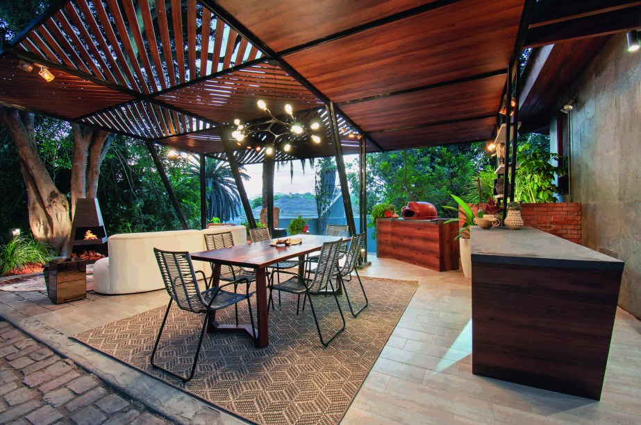 Fiorella Henríquez - Terraza del Ficus. Um terraço aberto à natureza, localizado sob um grande ficus que é o ponto de inspiração para esta proposta. O design deste terraço evoca um refúgio onde se procura conectar com a natureza, viver o espaço e criar grandes momentos. A proposta explora os sentidos através da seleção de materiais que vão do rústico ao moderno, criando um ambiente acolhedor e funcional com elementos orgânicos, arte e iluminação indireta com impacto visual que combinam com uma atmosfera de descontração e elegância atemporal.