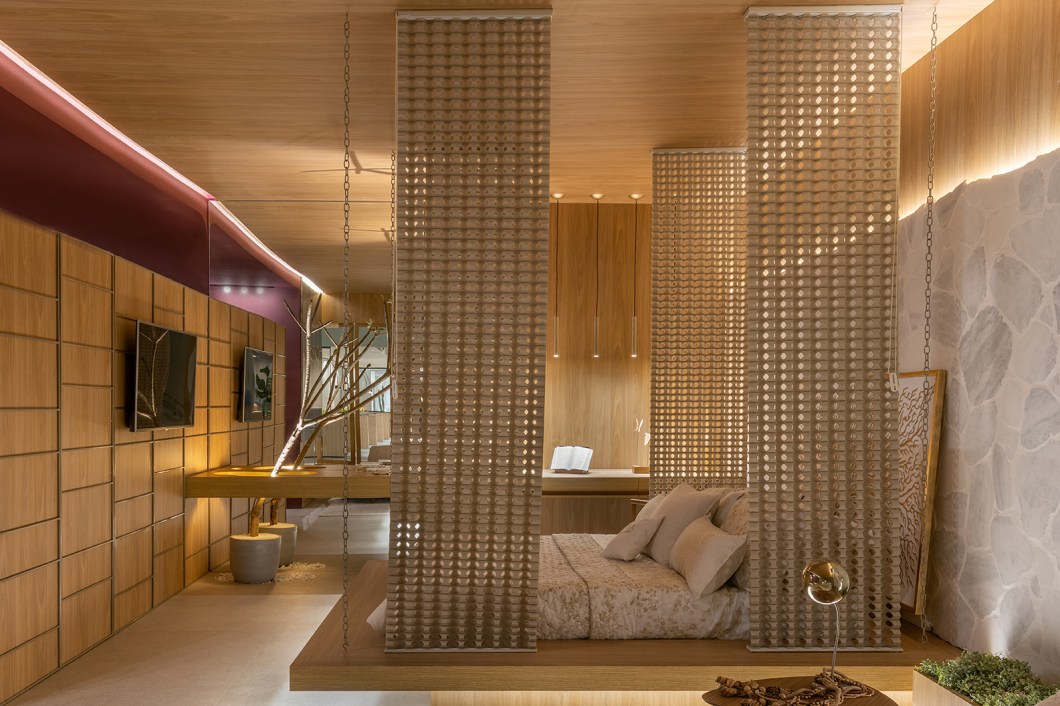 LC Arquitetos - A Suíte do Hotel. A suíte do hotel, projetada por Luciana Cunha, é composta por elementos naturais como madeira, pedras e plantas, e também mistura linhas retas e orgânicas. O espaço de 45 m² tem janelas sanfonadas e vazadas, a madeira e a cor vinho quente têm continuidade funcionando como pano de fundo para outros materiais, como o mármore grego com acabamento em semente de acácia. Outro destaque para o tema é o hall que traz em perspectiva o ponto de fuga. Uma árvore de outono completa o projeto. LC Arquitetos - A Suíte do Hotel. A suíte do hotel, projetada por Luciana Cunha, é composta por elementos naturais como madeira, pedras e plantas, e também mistura linhas retas e orgânicas. O espaço de 45 m² tem janelas sanfonadas e vazadas, a madeira e a cor vinho quente têm continuidade funcionando como pano de fundo para outros materiais, como o mármore grego com acabamento em semente de acácia. Outro destaque para o tema é o hall que traz em perspectiva o ponto de fuga. Uma árvore de outono completa o projeto.