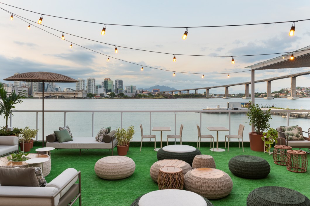 Christian Vieira, Vinicius de Oliveira e Sávio Lombardi - Lounge de Eventos. Um ambiente que interage com a paisagem por meior de lounges projetados no local, com o propósito de um espaço de descontração e contemplação da baía de Vitória. Assim foi a concepção criada pelos profissionais para o ambiente em que chama atenção por um grande painel pintado por artistas capixabas, em uma fachada que abraça o ambiente. Mobiliários de design contribuem de forma harmônica e dinâmica, misturando arte e natureza em uma atmosfera que é um convite para realização de variados eventos e encontros animados. Christian Vieira, Vinicius de Oliveira e Sávio Lombardi - Lounge de Eventos. Um ambiente que interage com a paisagem por meior de lounges projetados no local, com o propósito de um espaço de descontração e contemplação da baía de Vitória. Assim foi a concepção criada pelos profissionais para o ambiente em que chama atenção por um grande painel pintado por artistas capixabas, em uma fachada que abraça o ambiente. Mobiliários de design contribuem de forma harmônica e dinâmica, misturando arte e natureza em uma atmosfera que é um convite para realização de variados eventos e encontros animados.
