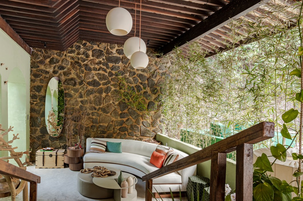 Joilson Barbosa, Luis Damarant, Tânia e Paula Facchinetti - Portal das Palmeiras. A escada sinuosa, ladeada por exuberantes palmeiras, conduz o visitante a um ambiente destinado ao descanso, com mobiliários e objetos decorativos que proporcionam conforto e traz a sensação de bem-estar. A ambientação integra o jardim ao lounge. O elemento água foi o ponto de partida do quarteto para o projeto que criou uma cascata e um pequeno lago artificial que garantem tranquilidade e frescor ao espaço. Pedrisco e vegetações fazem uma transição entre o jardim externo e o piso interno. A água caindo no lago é um estimulante sensorial e complementa a beleza e harmonia do espaço. Joilson Barbosa, Luis Damarant, Tânia e Paula Facchinetti - Portal das Palmeiras. A escada sinuosa, ladeada por exuberantes palmeiras, conduz o visitante a um ambiente destinado ao descanso, com mobiliários e objetos decorativos que proporcionam conforto e traz a sensação de bem-estar. A ambientação integra o jardim ao lounge. O elemento água foi o ponto de partida do quarteto para o projeto que criou uma cascata e um pequeno lago artificial que garantem tranquilidade e frescor ao espaço. Pedrisco e vegetações fazem uma transição entre o jardim externo e o piso interno. A água caindo no lago é um estimulante sensorial e complementa a beleza e harmonia do espaço.