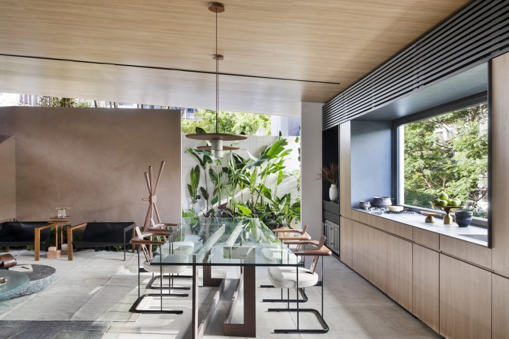 Navarro Arquitetura – Casa Araxá Navarro Arquitetura - Casa Araxá. Projeto da CASACOR São Paulo 2023. NA foto, sala de jantar com mesa de vidro, cozinha e jardim.