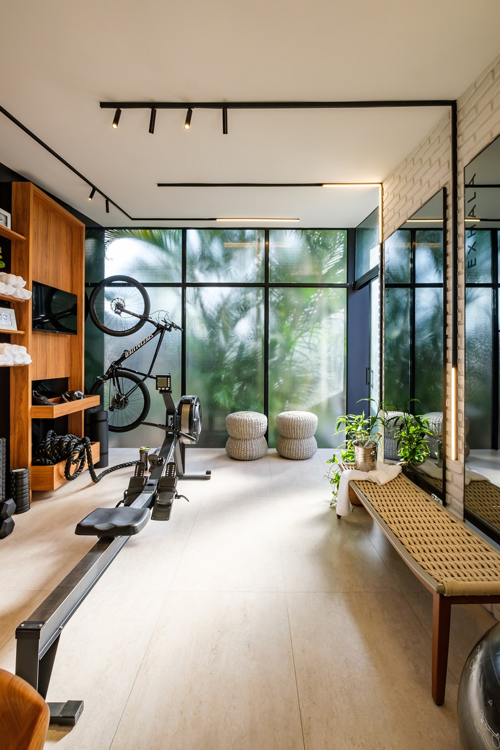 andrea-vargas-paola-blanco-silvana-belmonte-gimnasio-en-casa-casacor-bolivia-2023-credito-alvaro-mier-(2) Andrea Vargas, Paola Blanco e Silvana Belmonte - Gimnasio en Casa. Projeto da CASACOR Bolívia 2023. Na foto, academia com espelhos, parede de tijolinhos e equipamentos de ginástica.