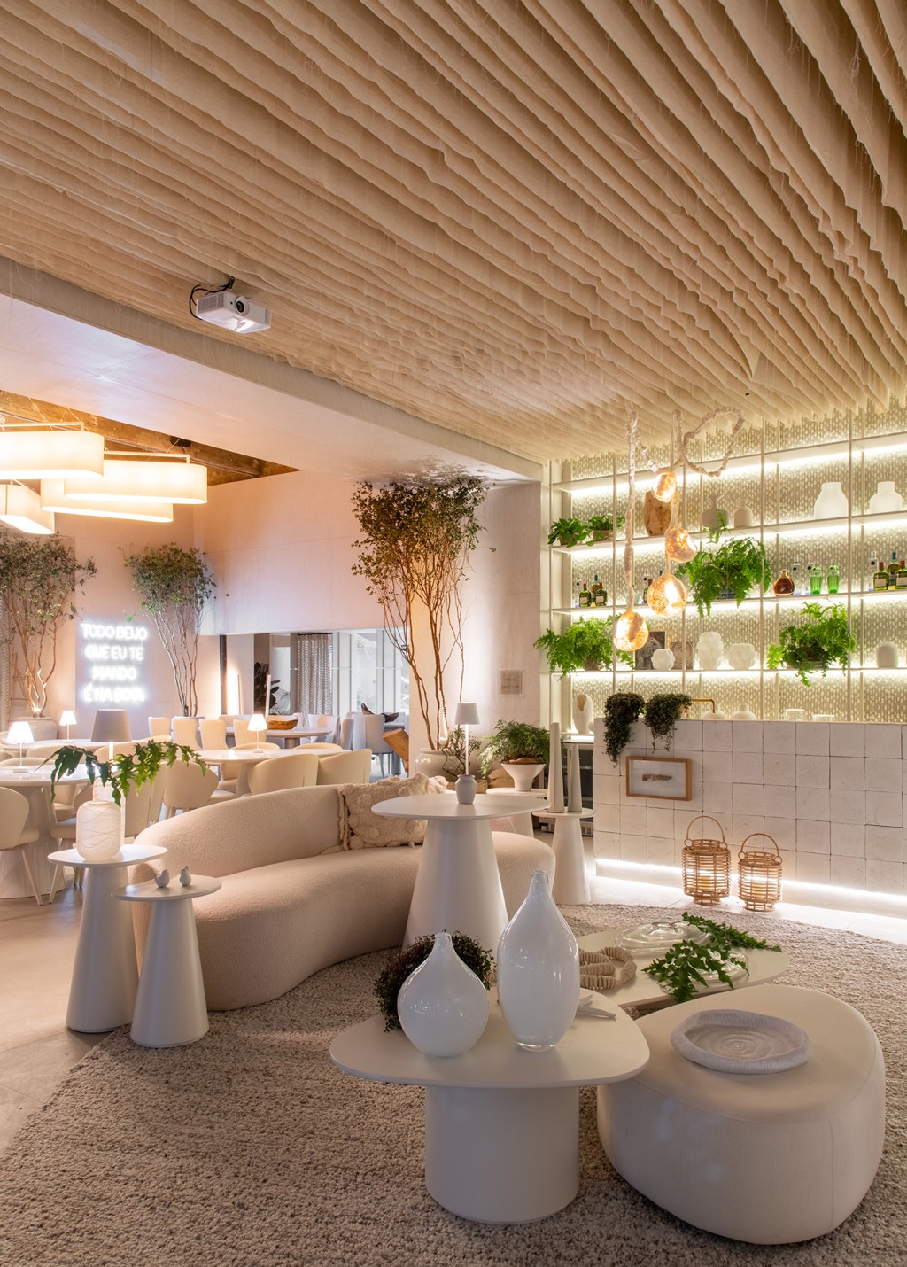 carla-felippi-casa-em-mykonos-myk-casacor-sao-paulo-2023-credito-favaro-jr (4) Carla Felippi - Casa em Mykonos | MYK. Projeto da CASACOR São Paulo 2023. Na foto, restaurante com sofa, mesasm tapete e estante/bar iluminada.