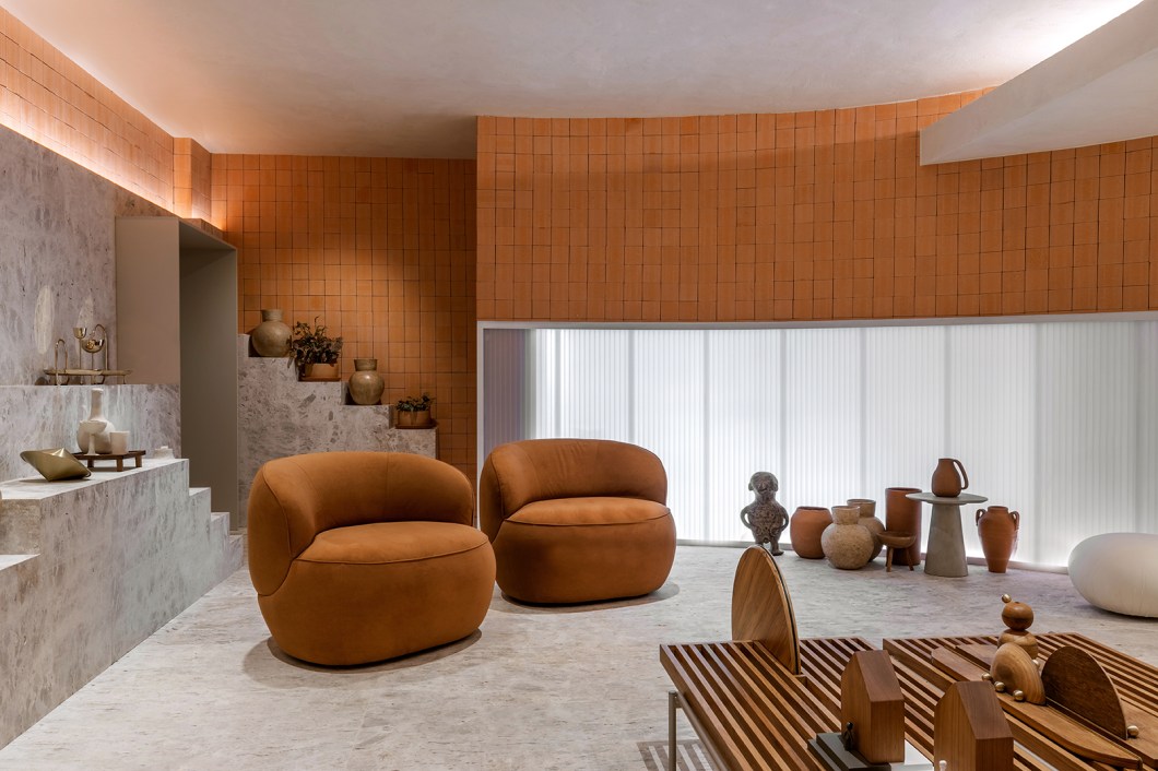 Marcos Lula - Lounge Origem. Estreante na CASACOR, o arquiteto assina o projeto de 74 m², que proporciona um equilíbrio entre experiência e arquitetura, homenageando de forma sutil as mães e os filhos. O acesso ao espaço é composto por meio de uma representação simbólica e principalmente sinestésica do útero das mães. Para isso, o pé-direito é reduzido, caixas de som reproduzem relatos de diversas mães, paredes são revestidas por cortinas a iluminação é indireta e mais suave. Há formas curvas, jarros de vidro com água em diferentes níveis e móveis rústicos. A lajota de terracota natural está presente em todo o ambiente para simbolizar a origem, o básico, e trazer uma memória afetiva de conforto e lar.