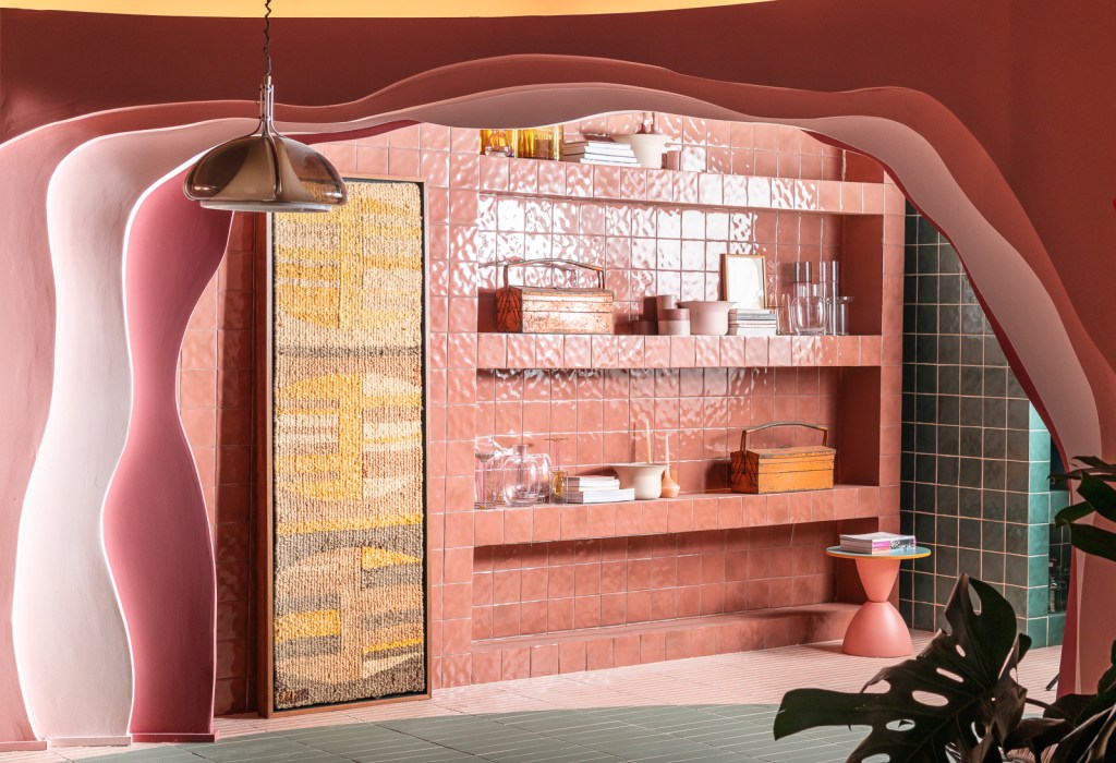 Ricardo Abreu - Casa Coral. Projeto da CASACOR São Paulo 2023. NA foto, estante de cerâmica rosa, tapeçaria e parede com recorte orgânico.