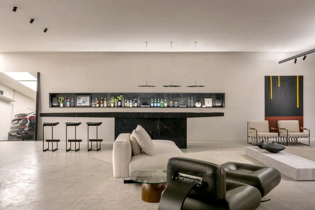 Sammea Vilarinho - Lounge Garagem. Projeto da CASACOR Goiás 2023. Na foto, garagem com sofá, bar e poltronas,