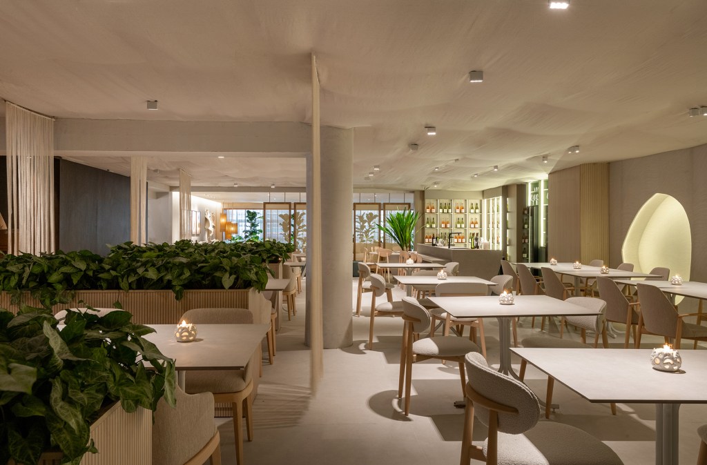 Vilaville Arquitetura - Restaurante Horta. Projeto da CASACOR São Paulo 2023. Na foto, mesas, cadeiras, adega e nichos iluminados.