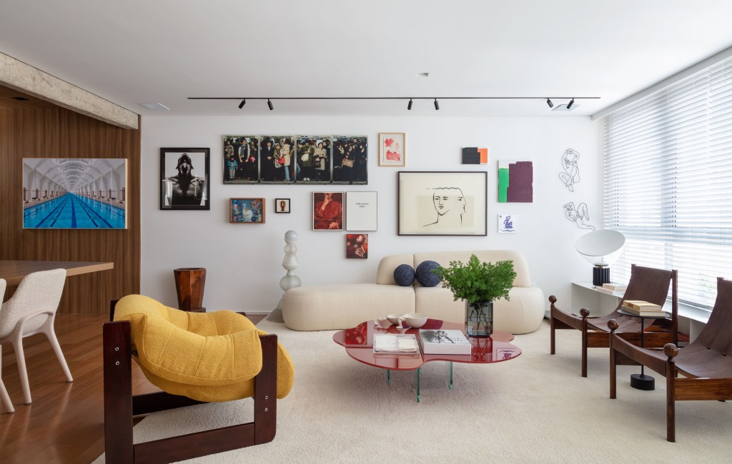 Obras de arte e móveis de design marcam o apê de colecionador. Projeto de Nop Arquitetura. Na foto, sala de estar com quadros, sofá curvo e poltronas.