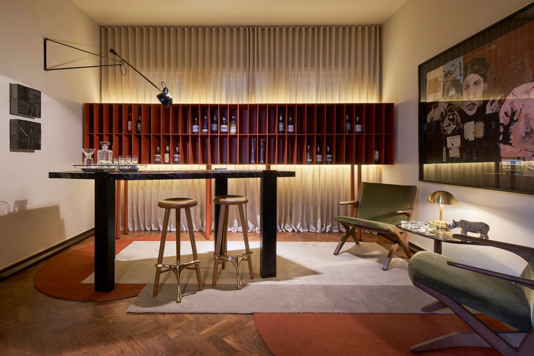 Dunia Zaidan Arquitetura - Sala de aperitivos. Nas casas antigas, era um cantinho frequente, que depois caiu em desuso e, neste projeto, foi resgatado com muita bossa. Com design delgado, a bancada assimétrica de pedra, releitura contemporânea dos antigos bares das residências, tem, logo atrás, prateleiras e escaninhos que trabalham cheios e vazios com garrafas de bebidas diversas. Ao lado, as sugestivas poltronas são intercaladas por mesinha com luminária. Dunia Zaidan Arquitetura - Sala de aperitivos. Nas casas antigas, era um cantinho frequente, que depois caiu em desuso e, neste projeto, foi resgatado com muita bossa. Com design delgado, a bancada assimétrica de pedra, releitura contemporânea dos antigos bares das residências, tem, logo atrás, prateleiras e escaninhos que trabalham cheios e vazios com garrafas de bebidas diversas. Ao lado, as sugestivas poltronas são intercaladas por mesinha com luminária.