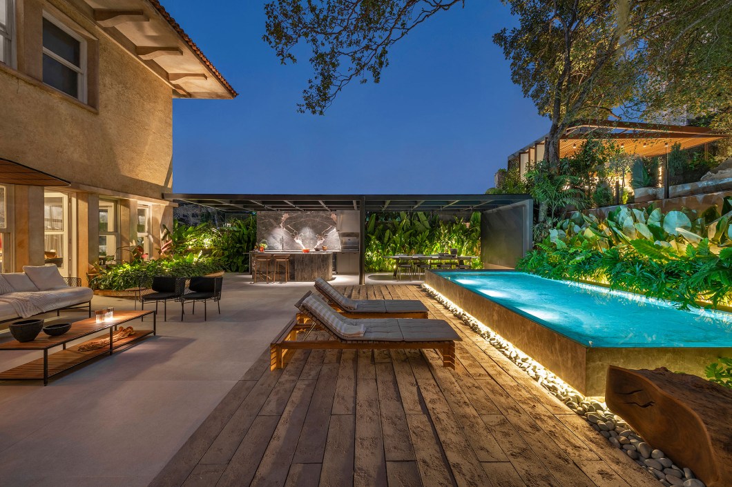 Estela Netto Arquitetura - Tributo aos 20. Uma área externa voltada para o lazer, lugar para celebrar, receber, desfrutar e conviver. Com espaço gourmet, piscina, lounge e adega, explora a beleza de pedras brasileiras como o mármore dolomita e o quartzito, que foram trabalhadas à mão, in loco. Colorido pelo verde do exuberante paisagismo, alia também a tecnologia, presente no painel de led, na sonorização do espaço e em outros detalhes. Estela Netto Arquitetura - Tributo aos 20. Uma área externa voltada para o lazer, lugar para celebrar, receber, desfrutar e conviver. Com espaço gourmet, piscina, lounge e adega, explora a beleza de pedras brasileiras como o mármore dolomita e o quartzito, que foram trabalhadas à mão, in loco. Colorido pelo verde do exuberante paisagismo, alia também a tecnologia, presente no painel de led, na sonorização do espaço e em outros detalhes.