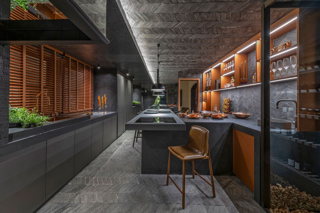 Andréa Buratto - Cozinha cave. Pensado como uma cozinha cave, o ambiente foge do lugar comum. É um convite às experiências e ao convívio, destinado à reuniões prazerosas para uma degustação acompanhada de bons vinhos de uma adega bem elaborada. Sobreposições, texturas e uma harmoniosa mistura de materiais realçam o charme do espaço, com destaque para a releitura criativa da ardósia - a negra e a cinza - que reveste parede e parte do teto. Andréa Buratto - Cozinha cave. Pensado como uma cozinha cave, o ambiente foge do lugar comum. É um convite às experiências e ao convívio, destinado à reuniões prazerosas para uma degustação acompanhada de bons vinhos de uma adega bem elaborada. Sobreposições, texturas e uma harmoniosa mistura de materiais realçam o charme do espaço, com destaque para a releitura criativa da ardósia - a negra e a cinza - que reveste parede e parte do teto.