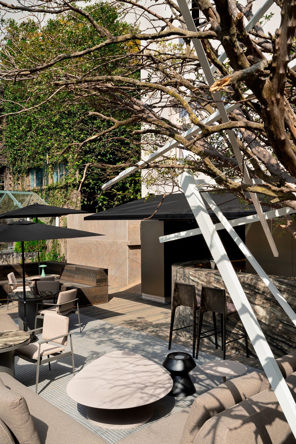Cris Capanema - Bar. Projeto da CASACOR Minas Gerais 2023. Na foto, bar ao ar livre, com balcão, mesa, cadeira e árvores.