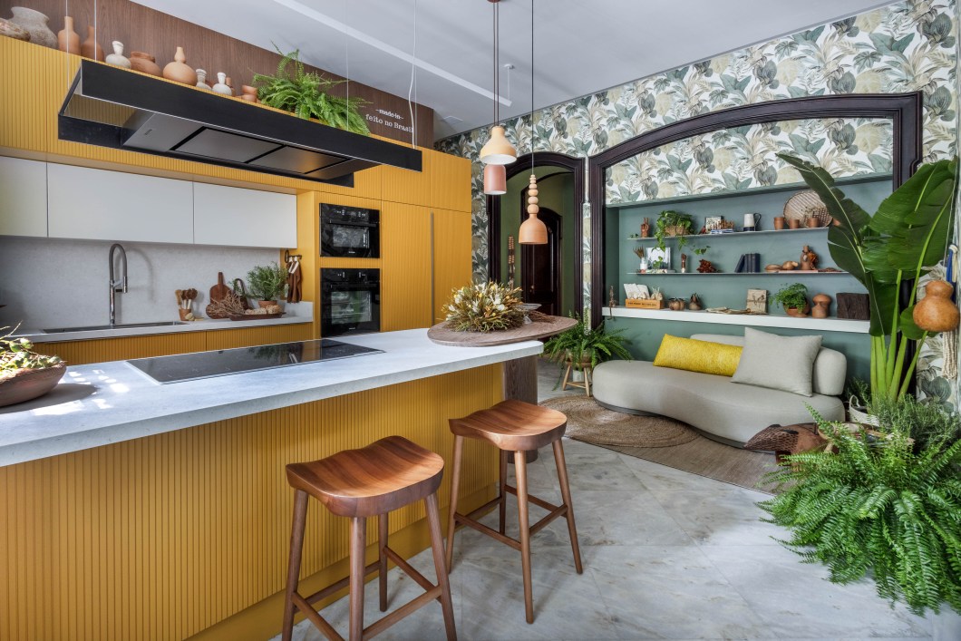 Amanda Miranda - Cozinha do Chef - Raízes. Ambiente funcional onde acontecem degustações, a Cozinha do Chef – Raízes celebra a brasilidade com um mix de texturas e cores, que inclui peças artesanais de palha, cerâmica e madeira e uma padronagem de folhagens bem tropicais nas paredes. A ambientação criada por Amanda Miranda aguça os sentidos. Logo na entrada, o Hall Oca ganha uma parede forrada de piaçava numa referência tanto às habitações indígenas quanto ao trabalho dos Irmãos Campana (em homenagem a Fernando, falecido recentemente). Tudo isso sem abrir mão da tecnologia necessária para uma cozinha bem contemporânea. Amanda Miranda - Cozinha do Chef - Raízes. Ambiente funcional onde acontecem degustações, a Cozinha do Chef – Raízes celebra a brasilidade com um mix de texturas e cores, que inclui peças artesanais de palha, cerâmica e madeira e uma padronagem de folhagens bem tropicais nas paredes. A ambientação criada por Amanda Miranda aguça os sentidos. Logo na entrada, o Hall Oca ganha uma parede forrada de piaçava numa referência tanto às habitações indígenas quanto ao trabalho dos Irmãos Campana (em homenagem a Fernando, falecido recentemente). Tudo isso sem abrir mão da tecnologia necessária para uma cozinha bem contemporânea.