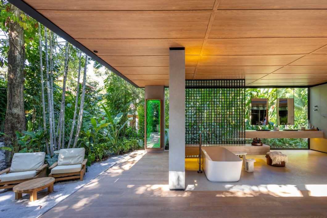 João Panaggio - Pavilhão Deca. Uma espécie de casa-spa, o ambiente criado pelo arquiteto João Panaggio para a Deca buscou inspiração nas termas romanas para fazer da água seu elemento central. Em formato de pavilhão leve e monolítico – numa referência ao nosso modernismo tropical -, a casa é totalmente conectada à natureza e pensada como um espaço premium para hóspedes em busca de relaxamento. No eixo principal da construção, uma piscina em volume ajuda a setorizar os ambientes, regendo o percurso da planta circular. O mobiliário traz madeira nacional, tecidos crus e estantes esculturais metálicas. João Panaggio - Pavilhão Deca. Uma espécie de casa-spa, o ambiente criado pelo arquiteto João Panaggio para a Deca buscou inspiração nas termas romanas para fazer da água seu elemento central. Em formato de pavilhão leve e monolítico – numa referência ao nosso modernismo tropical -, a casa é totalmente conectada à natureza e pensada como um espaço premium para hóspedes em busca de relaxamento. No eixo principal da construção, uma piscina em volume ajuda a setorizar os ambientes, regendo o percurso da planta circular. O mobiliário traz madeira nacional, tecidos crus e estantes esculturais metálicas.