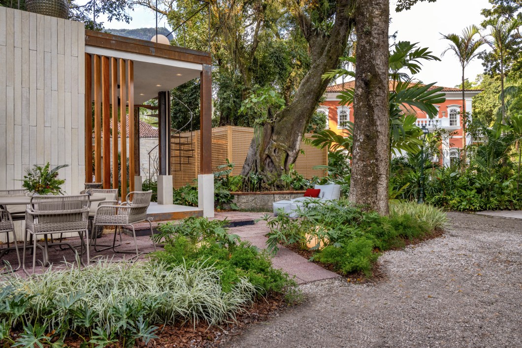Karyne Lima - Jardim Caminhos e Conexões. Para o bangalô Caminhos, a paisagista Karyne Lima criou um jardim com vegetação bem tropical, como toda a mata que já ocupa a área externa do Instituto Brando Barbosa. Mas aqui o que chama a atenção é a diversidade de texturas e tonalidades das folhagens verdes. São espécies como Dionela, Bipinnatifidum, Liriope e Ravenala que criam um caminho orgânico, como se sempre estivessem estado ali. E elas aparecem também no telhado do bangalô, que reproduz este traçado em linhas curvas criando um gostoso ambiente extra de estar, de onde se pode apreciar todo o jardim. Karyne Lima - Jardim Caminhos e Conexões. Para o bangalô Caminhos, a paisagista Karyne Lima criou um jardim com vegetação bem tropical, como toda a mata que já ocupa a área externa do Instituto Brando Barbosa. Mas aqui o que chama a atenção é a diversidade de texturas e tonalidades das folhagens verdes. São espécies como Dionela, Bipinnatifidum, Liriope e Ravenala que criam um caminho orgânico, como se sempre estivessem estado ali. E elas aparecem também no telhado do bangalô, que reproduz este traçado em linhas curvas criando um gostoso ambiente extra de estar, de onde se pode apreciar todo o jardim.